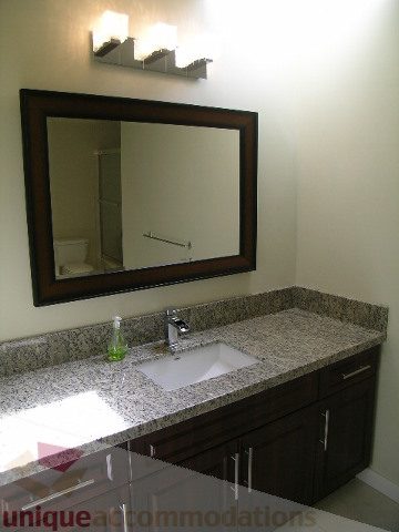 Bathroom with granite countertop and dark wood cabinets. - 4215 Evergreen Ave, West Vancouver