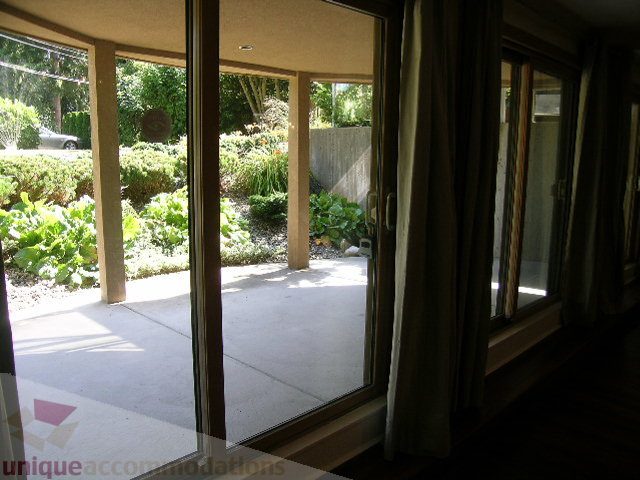 Bright living room with sliding glass doors leading to a garden, hardwood floors, and a view of the backyard. - 4215 Evergreen Ave, West Vancouver