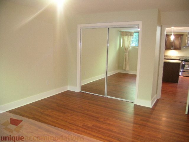 Bright living room with hardwood floors and sliding glass doors leading to a kitchen. - 4215 Evergreen Ave, West Vancouver