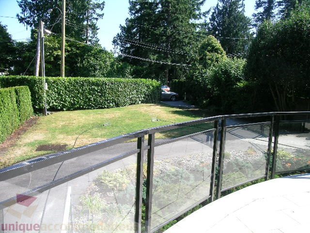 Balcony with glass railings and view of greenery and street below. - 4215 Evergreen Ave, West Vancouver