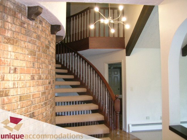 Staircase leading to upper level with brick wall and wooden railings. - 5568 Greenleaf Road, West Vancouver