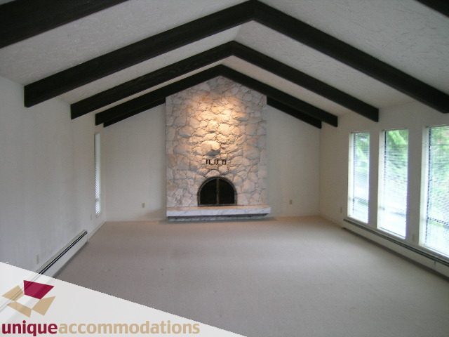 Spacious living room with stone fireplace, vaulted ceiling, and large windows. - 5568 Greenleaf Road, West Vancouver
