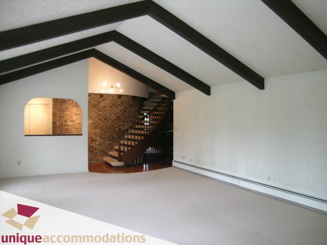 Spacious attic room with exposed beams and a staircase leading up. - 5568 Greenleaf Road, West Vancouver