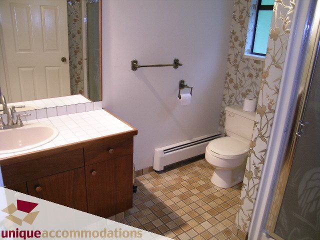 Bathroom with wooden vanity, tiled floor, and floral wallpaper. - 5568 Greenleaf Road, West Vancouver