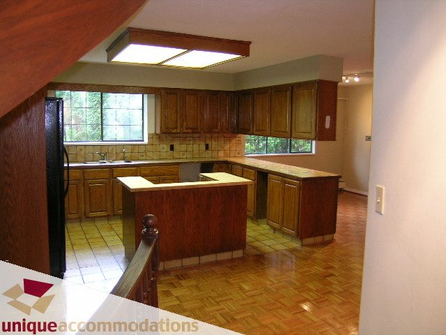 Bright kitchen with wooden cabinets, parquet floors, and a city view. - 5568 Greenleaf Road, West Vancouver