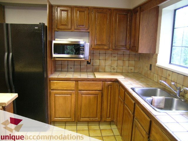 Bright kitchen with wooden cabinets, stainless steel appliances, and tiled backsplash. - 5568 Greenleaf Road, West Vancouver
