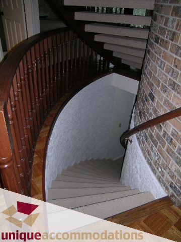 Staircase with wooden banister and brick wall leading to upper level. - 5568 Greenleaf Road, West Vancouver