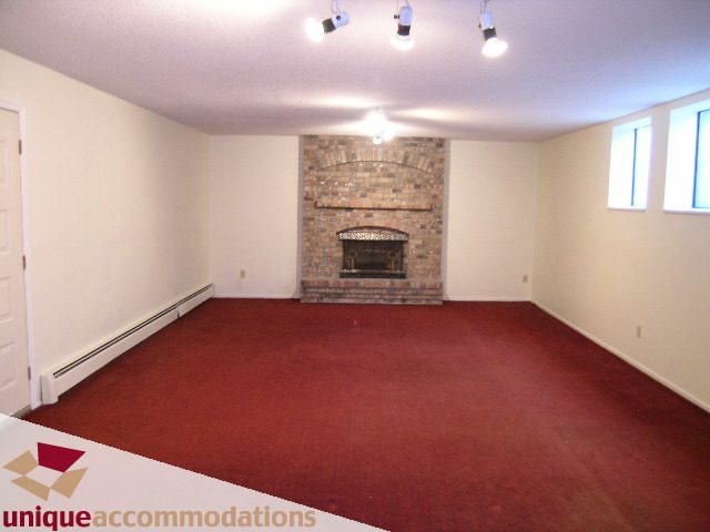 Spacious living room with red carpet and brick fireplace. - 5568 Greenleaf Road, West Vancouver