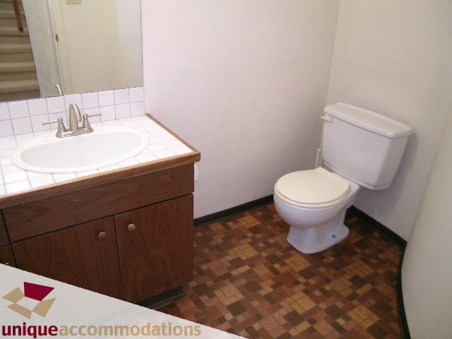 Bathroom with wooden cabinets, white sink, and mosaic tile floor. - 5568 Greenleaf Road, West Vancouver