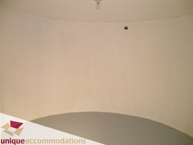 Empty living room with a round table and plain walls. - 5568 Greenleaf Road, West Vancouver