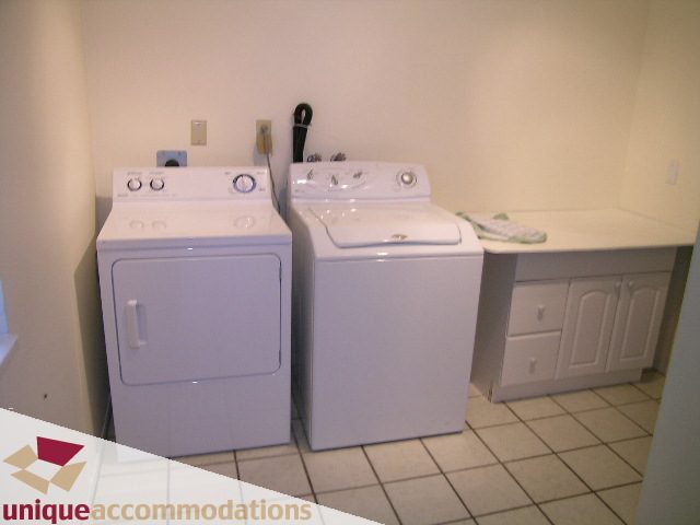 Bright laundry room with white appliances and tiled floor. - 5568 Greenleaf Road, West Vancouver