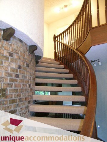 Staircase with wooden banister and brick wall. - 5568 Greenleaf Road, West Vancouver