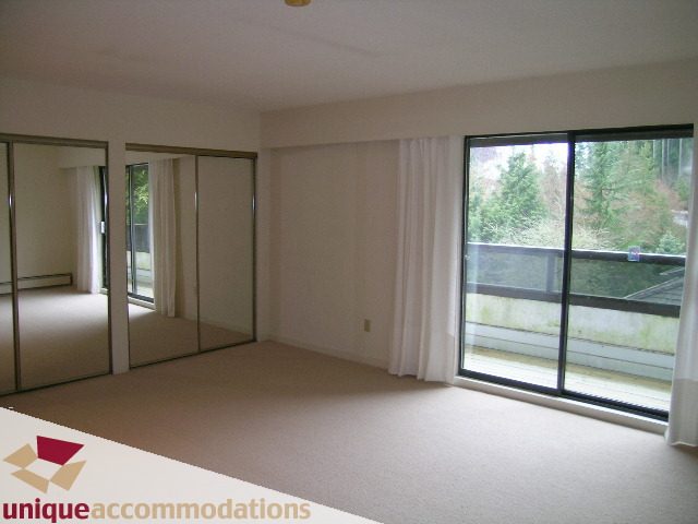 Spacious bedroom with large windows and mirrored closet doors. - 5568 Greenleaf Road, West Vancouver