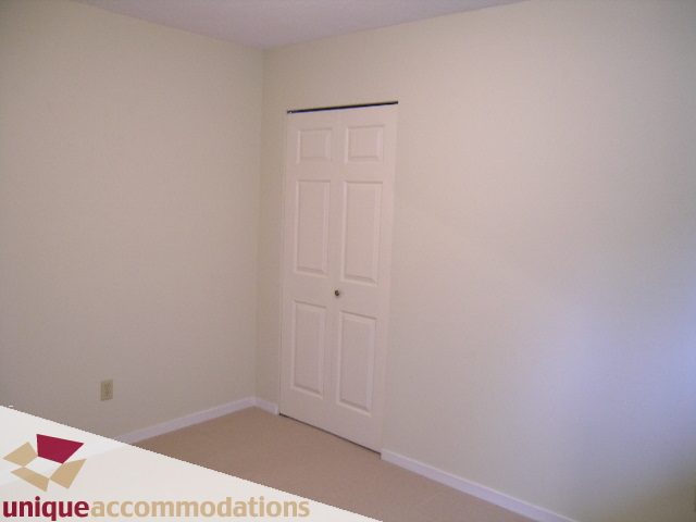 Empty bedroom with white walls and a closed door. - 5568 Greenleaf Road, West Vancouver