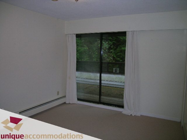 Bright living room with large windows and a view of greenery. - 5568 Greenleaf Road, West Vancouver