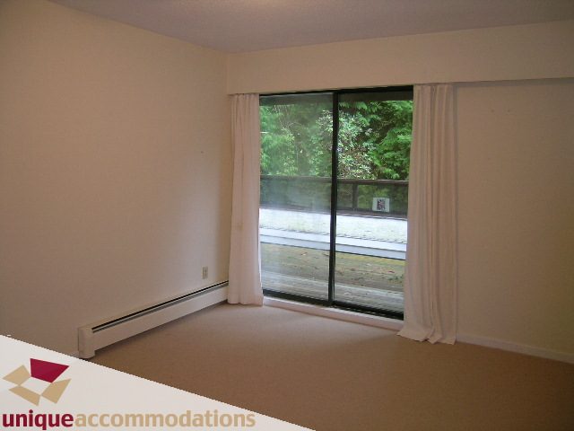 Bright living room with large windows, natural light, and a view of greenery. - 5568 Greenleaf Road, West Vancouver