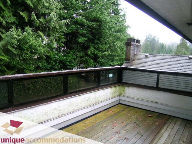 Furnished deck with wooden flooring and a view of lush green trees. - 5568 Greenleaf Road, West Vancouver