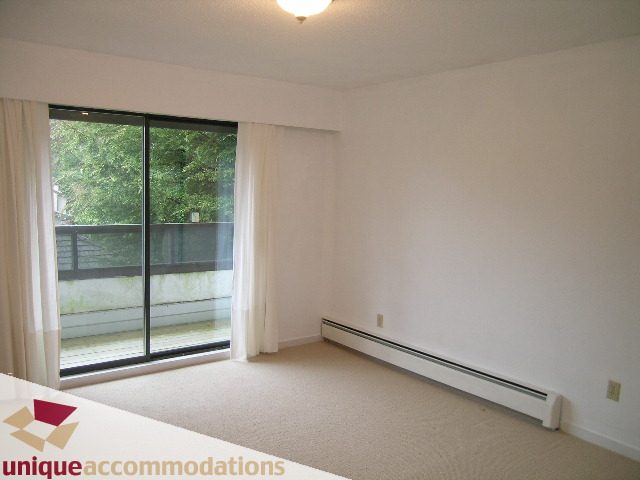 Spacious living room with sliding glass doors and city view. - 5568 Greenleaf Road, West Vancouver