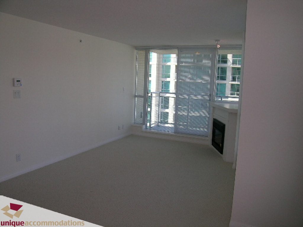 Spacious bedroom with large windows offering a city view and a sleek countertop. - 1108 - 188 East Esplanade Ave, North Vancouver