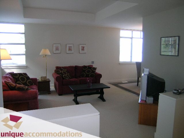Spacious living room with red armchairs, modern decor, and large windows. - 8583 Seascape Lane, West Vancouver