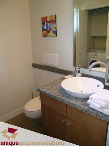 Spacious bathroom with granite countertops and modern sink, featuring a stylish painting above the toilet. - 8583 Seascape Lane, West Vancouver