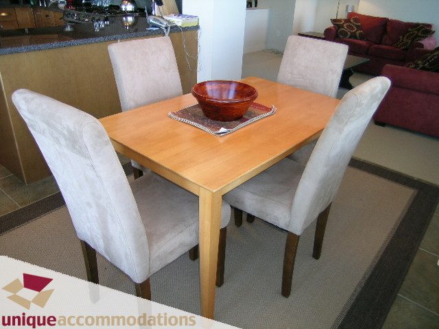 Modern dining area with light wood table, cream chairs, and a wooden bowl centerpiece. - 8583 Seascape Lane, West Vancouver