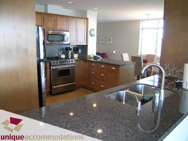 Modern kitchen with granite countertops and stainless steel appliances, perfect for a cozy stay. - 8583 Seascape Lane, West Vancouver