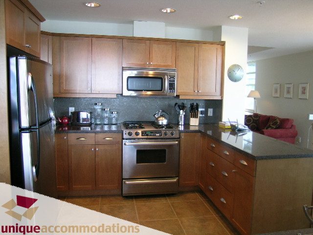 Modern kitchen with granite countertops, stainless steel appliances, and wooden cabinets. - 8583 Seascape Lane, West Vancouver