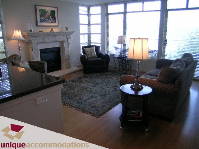 Spacious living room with hardwood floors, large windows, and a cozy fireplace. - 8583 Seascape Lane, West Vancouver