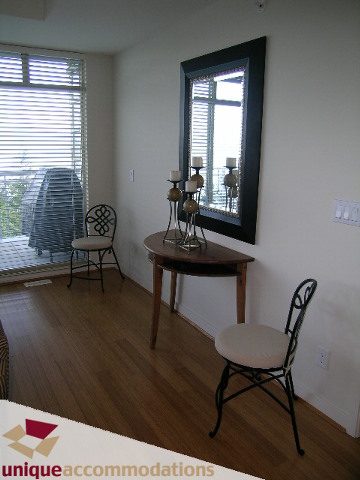 Spacious living room with hardwood floors, a cozy corner chair, and a stylish candelabra. - 8583 Seascape Lane, West Vancouver