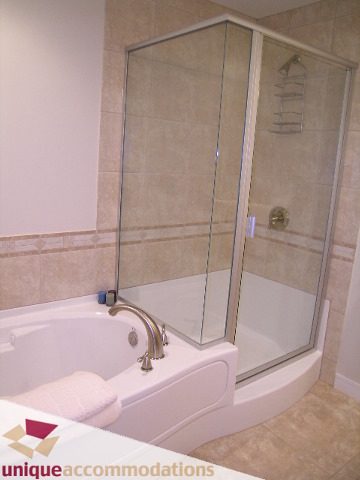 Spacious bathroom with a corner tub and glass shower, featuring a sleek countertop and neutral tones. - 8583 Seascape Lane, West Vancouver