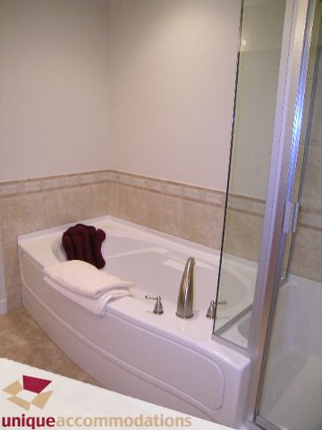 Spacious bathroom with a corner bathtub, glass shower, and neatly folded towels. - 8583 Seascape Lane, West Vancouver