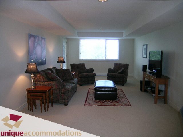 Spacious living room with large windows, cozy furniture, and a central coffee table. - 8583 Seascape Lane, West Vancouver
