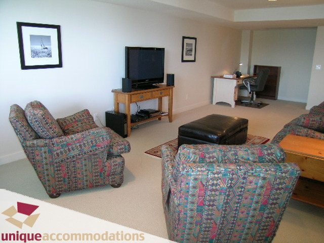 Spacious living room with patterned furniture, a TV, and a desk in the corner. - 8583 Seascape Lane, West Vancouver