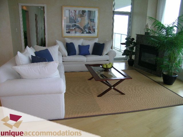 Spacious living room with white sofas, blue pillows, and a fireplace, perfect for relaxation. - 3401 - 1111 West Pender, Vancouver Downtown