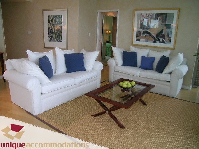 Spacious living room with white couches, blue throw pillows, and a modern coffee table. - 3401 - 1111 West Pender, Vancouver Downtown