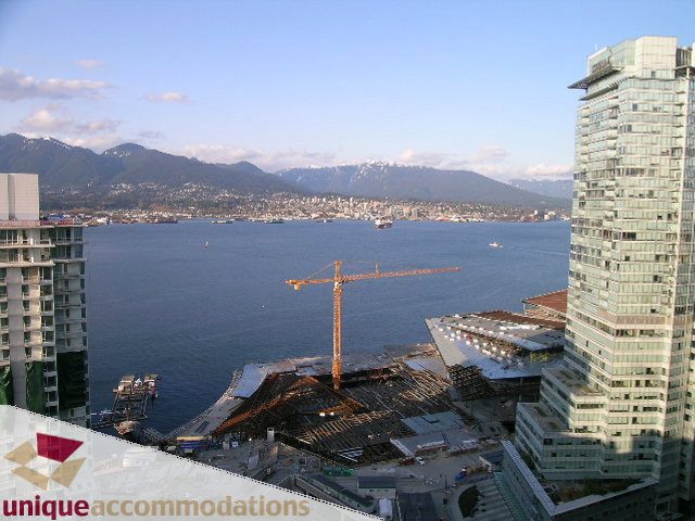 Spacious 2-bedroom + den condo with stunning city and water views, featuring modern furnishings and a balcony.