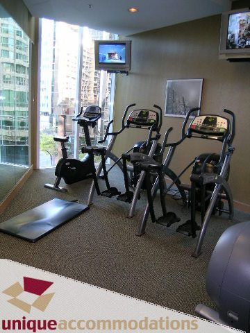 Bright gym with city view, cardio equipment, and wall-mounted TV. - 3401 - 1111 West Pender, Vancouver Downtown