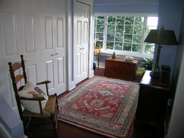 Bright living room with red patterned rug, wooden furniture, and large window view. - 1152 West 7th Ave, Vancouver West Side