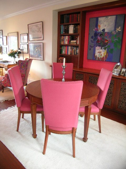 Dining room with pink chairs, wooden table, bookshelves, and vibrant artwork. - 1152 West 7th Ave, Vancouver West Side