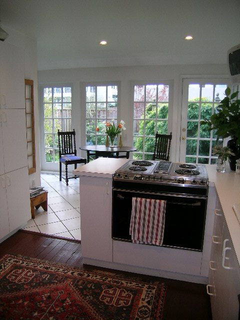 Bright kitchen with white cabinets, hardwood floors, and a city view through large windows. - 1152 West 7th Ave, Vancouver West Side