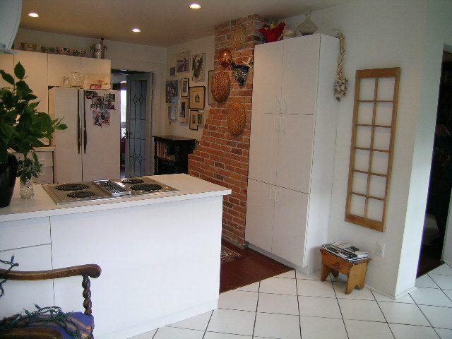 Bright kitchen with white cabinets, brick accent wall, and tiled floor. - 1152 West 7th Ave, Vancouver West Side