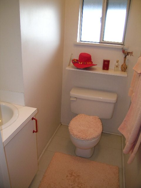 Bright bathroom with white fixtures and pink accents, featuring a red hat on a shelf. - 1152 West 7th Ave, Vancouver West Side