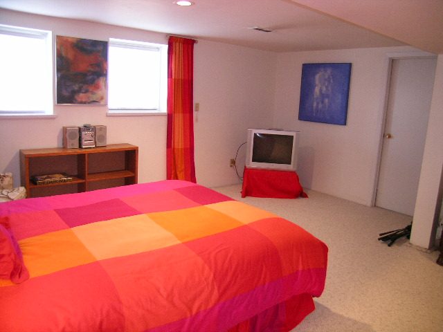 Bright bedroom with colorful bedding and a small TV, modern decor. - 1152 West 7th Ave, Vancouver West Side