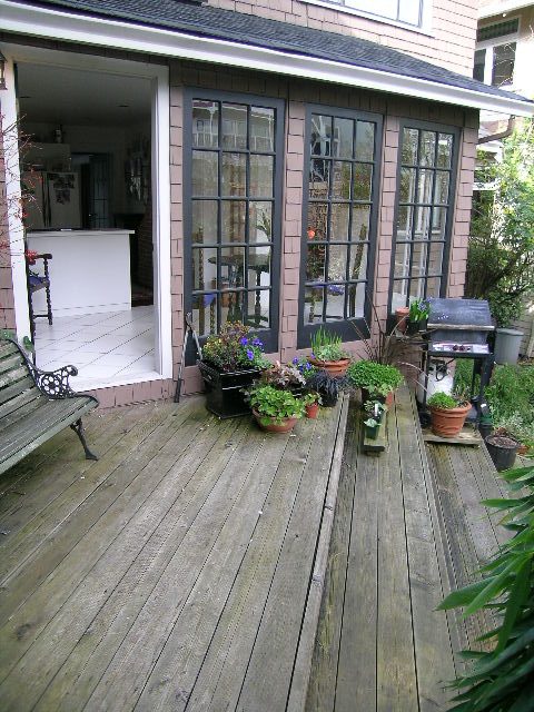 Bright sunroom with hardwood floors, potted plants, and a barbecue grill. - 1152 West 7th Ave, Vancouver West Side