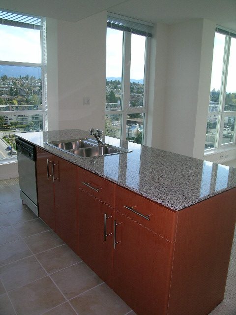 Bright kitchen with granite countertops, wooden cabinets, and a stunning city view. - 1801 - 188 East Esplanade, North Vancouver