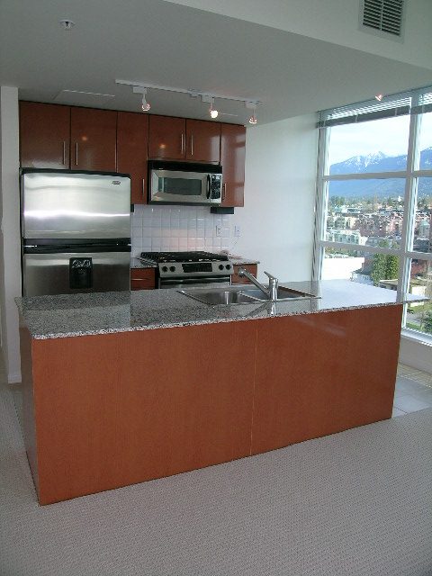 Modern kitchen with granite countertops and a city view. - 1801 - 188 East Esplanade, North Vancouver