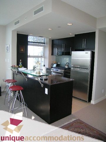 Bright kitchen with sleek black countertops and stainless steel appliances, featuring a modern city view. - 1905 - 638 Beach Cres, Vancouver Downtown