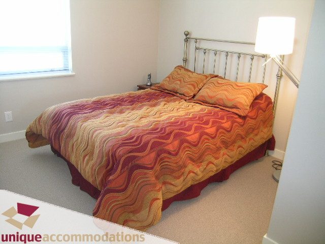 Furnished bedroom with a vibrant, wavy patterned bedspread and a metal headboard. - 1905 - 638 Beach Cres, Vancouver Downtown