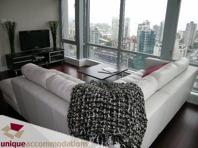 Furnished living room with white leather sofa, city view, hardwood floors, and modern decor. - 3104 - 1255 Seymour Street, Vancouver Downtown